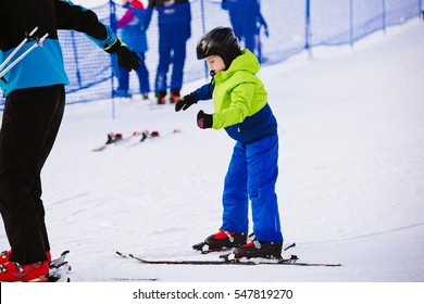 Child In A Black Ski Helmet Learns To Ski With Instructor. Child At Winter