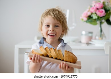 Child, blond toddler boy, holding wooden cutting board with homemade ciabatta bread, serving at homefreshlz baked bread