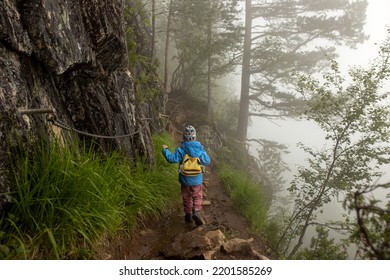 Child in blue jacket walking up the path to Rampestreken in Andalsnes. Norway on a very foggy day summertime