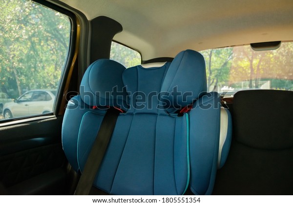 A child blue seat in the car, secured with seat belts\
in sunny summer day