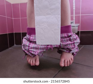 Child With Bowel Problems And Constipation Holds Toilet Paper Sitting On Toilet. Constipation In Children Concept