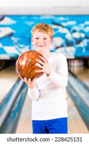 Child Bowling With Ball In Alley