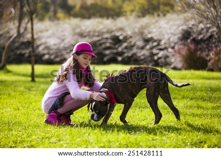 Child with a boxer dog at the city park