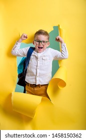 Child boy with book and bag breaking through yellow paper wall.  - Shutterstock ID 1458150362