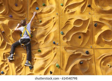 Child Boy Climbing A Rock Wall Outdoor - Bouldering. Free Climber Child Young Boy Practicing On Artificial Boulders In Gym