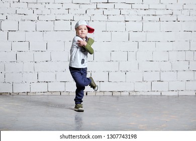 Child Boy Dancing. Cool Kid Hip Hop Break Dancing On Brick Wall Background. Little Man Movement, Expressions In Dance. Wears A Cap, Sneakers, Pants, T-shirt, Street Style.