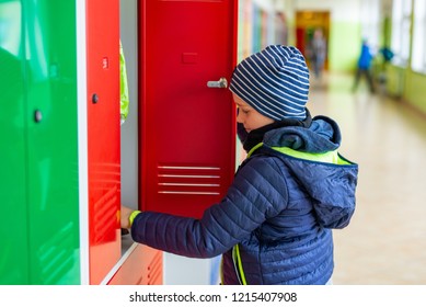 Child boy dressing his autumn jacket in school locker room - Powered by Shutterstock