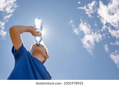 child boy drinking water from bottle outdoors on a hot sunny day  - Powered by Shutterstock