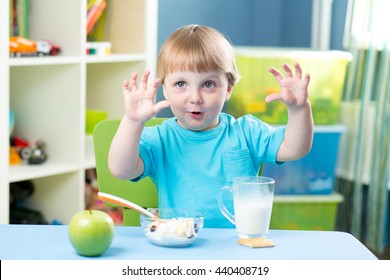 child boy eating apple at dinner in nursery at home