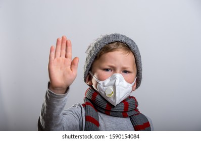 Child Boy In Face Mask Protection. School Boy Breathing Through Medical Mask Because Of Virus. School Kid In Scarf And Hat Protect From Sick. Hand With Sigh Ok And Fine. 