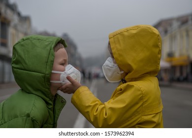 Child boy and girl walking outdoors with face mask protection. School boy breathing through medical mask because of smog and air pollution. Children in bright yellow rain coat.