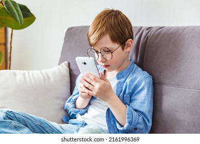 Child Boy In Glasses Plays Tablet. Concept Of Poor Eyesight, Harm Of Gadgets, Myopia