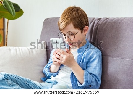 Child boy in glasses plays tablet. Concept of poor eyesight, harm of gadgets, myopia