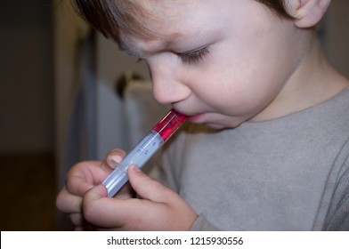 Child Boy Having Antipyretic Medicine With Measuring Syringe By Himself. Closeup 