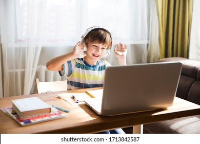 child boy in headphones is using a laptop and study online with video call teacher at home. homeschooling, distant learning
