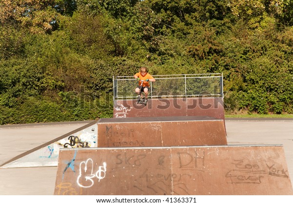 child, boy is jumping with a scooter in a skate parc
and enjoying it