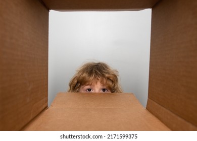 Child Boy Looking Surprised Into A Gift. Cheerful Cute Child Opening A Present. View From Inside Of The Box. Close Up Eyes Looking.