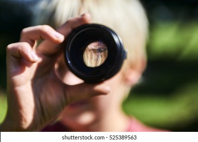 Child boy looking through camera lens