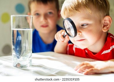 The child boy looking at water in a glass through magnifying glass - Powered by Shutterstock