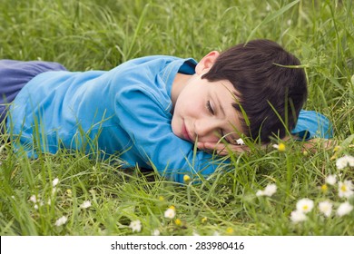 Child Boy Lying In Grass Resting And Relaxing With Closed Eyes