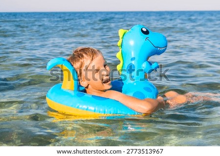 Child boy on inflatable float ring swimming enjoying in sea.Summer vacation,healthy outdoor sport activity for children.Kids beach fun.Water toy.