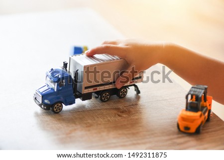 child boy playing toys on table at home / kid hands playing toy car truck 