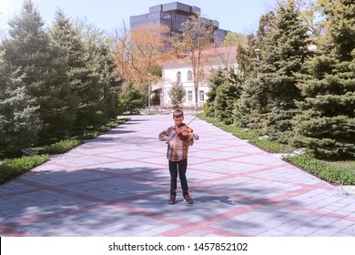 Child Boy Is Playing The Violin Standing In Alley On The Street In City. Little Musician With Nstrument At Street. Education Learn Play Violin Boy Teen Violinist Instrumentalist Performance Melody.