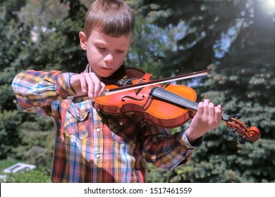 Child Boy Is Playing The Violin Standing In Park In The City. Portrait Of Little Musician. Education Learn Play Violin Boy Teen Violinist Instrumentalist Performance Melody.