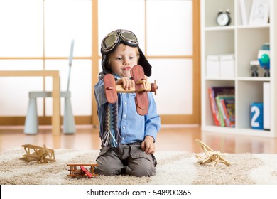 Child boy pretending to be pilot aviator. Kid playing with toy airplanes at home. Travel and dream concept - Powered by Shutterstock