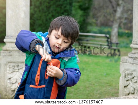 Child boy puting  things in a backpack, Schoo kid exploring with school trip, Children learning about seasons change on spring, Lean from nature.