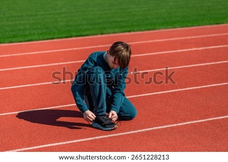 Child boy runner getting ready for training. Hands tying shoelace on running shoes before practice. Sport active lifestyle concept. Closeup. Running runner man tying laces sneakers shoes.