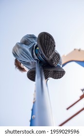 Child Boy Sliding Down By Fireman Pole Of Playground. Low Angle View