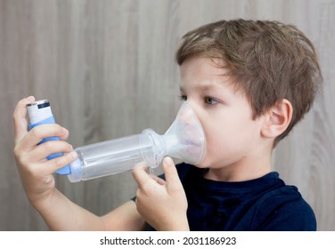 Child Boy Using Medical Spray For Breath. Inhaler, Spacer And Mask. Side View