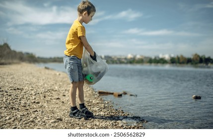 A child boy volunteer in gloves tidying up rubbish plastic garbage from the riverbank. Children take care of nature. - Powered by Shutterstock