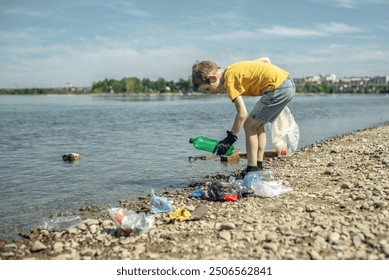 A child boy volunteer in gloves tidying up rubbish plastic garbage from the riverbank. Children take care of nature. - Powered by Shutterstock