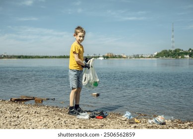 A child boy volunteer in gloves tidying up rubbish plastic garbage from the riverbank. Children take care of nature. - Powered by Shutterstock