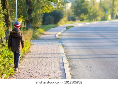 Child Boy Walking Alone On A Sidewalk