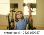 Child boy working out with dumbbells. Kids sport and active healthy life. Sport and kids training. Child workout kid in gym.