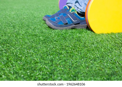 Child Boy In Yellow Playground Slide Over Artificial Green Grass Floor. Selective Focus