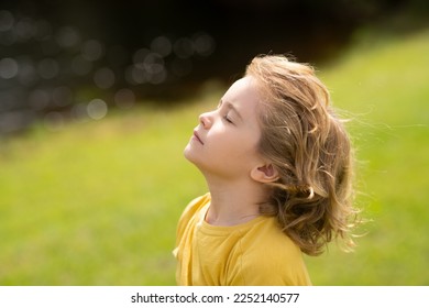 Child breathing fresh air. Child faith, praise and happiness and freedom. Kid resting in summer park. Kid put face to the sun, closed her eyes and feeds energy of nature, dreams. - Powered by Shutterstock