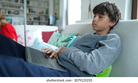 Child Browsing Internet On Laptop Computer Sitting At Sofa