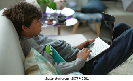 Child Browsing Internet On Laptop Computer Sitting At Sofa