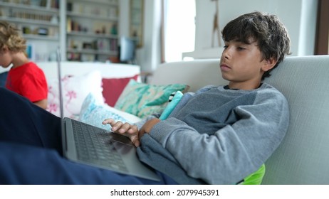 Child Browsing Internet On Laptop Computer Sitting At Sofa