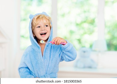 Child Brushing Teeth. Kids Tooth Brush And Paste. Little Baby Boy In Blue Bath Robe Or Towel Brushing His Teeth In White Bathroom With Window On Sunny Morning. Dental Hygiene And Heath For Children.