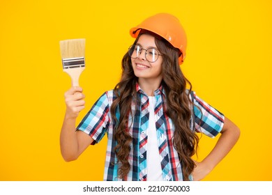 Child Builder In Hard Hat Helmet. Teenage Girl Painter With Painting Brush Tool Or Paint Roller. Teenager Worker Isolated On Yellow Background. Kids Renovation Concept.