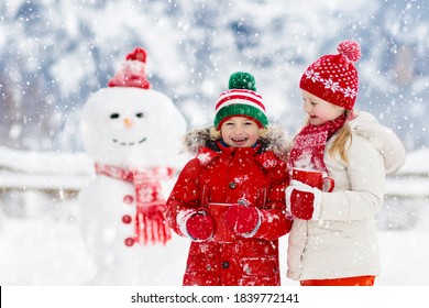 Child Building Snowman. Kids Build Snow Man. Boy And Girl Playing Outdoors On Snowy Winter Day. Outdoor Family Fun On Christmas Vacation In The Mountains. Children Play In Swiss Mountain Landscape.