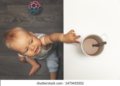 Child Burn And Scald Injury Concept - Little Boy Reaching For Hot Drink Mug On The Table