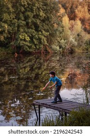 A Child By The River With A Fishing Rod. A Boy On A Fishing Trip.