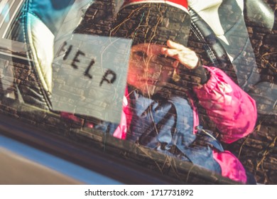 The Child In The Car Holds A Note With The Word Help