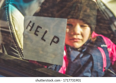 The Child In The Car Holds A Note With The Word Help